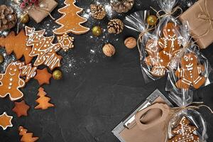 A Christmas gingerbread cookie in the shape of a Christmas tree in a cellophane packing on the background of a dark table. Christmas gift concept. photo