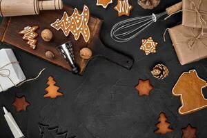 Christmas homemade gingerbread cookies, spices and cutting board on dark background with copy space for text top view. New year and christmas postcard photo