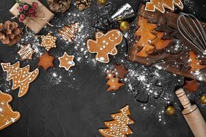 Christmas homemade gingerbread cookies, spices and cutting board on dark background with copy space for text top view. New year and christmas postcard photo