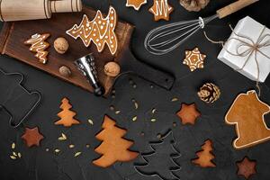 Christmas homemade gingerbread cookies, spices and cutting board on dark background with copy space for text top view. New year and christmas postcard photo