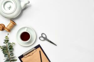 Still life with tea cup and the contents of a workspace composed. Different objects on white table. Flat lay photo