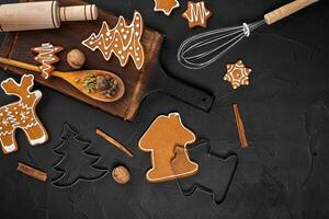 Christmas homemade gingerbread cookies, spices and cutting board on dark background with copy space for text top view. New year and christmas postcard photo