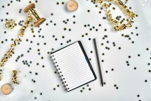 Flat Lay Christmas or Party Background with colored ribbons, decorations, confetti, and wrapping paper. Notepad for Text in Middle. photo
