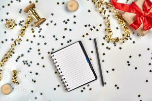 Flat Lay Christmas or Party Background with colored ribbons, decorations, confetti, and wrapping paper. Notepad for Text in Middle. photo