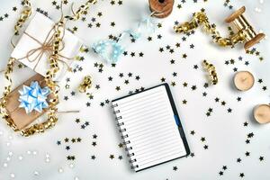 Flat Lay Christmas or Party Background with colored ribbons, decorations, confetti, and wrapping paper. Notepad for Text in Middle. photo