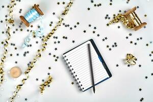 Flat Lay Christmas or Party Background with colored ribbons, decorations, confetti, and wrapping paper. Notepad for Text in Middle. photo