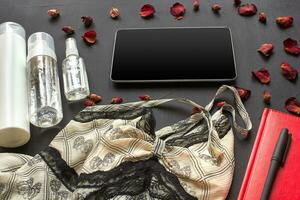 Composition with skin care cosmetic products without label and lace lingerie on a black desktop background. photo