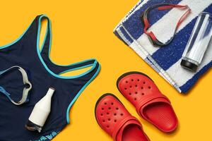 Flat lay summer pool accessories on a yellow background. Colorful beach wear. photo