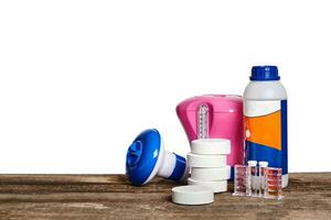 Equipment with chemical cleaning products and tools for the maintenance of the swimming pool on a wooden surface against white background. photo