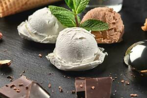 Gourmet creamy and chocolate ice cream served on a stone slate over a black background. photo