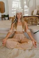 Stylish  blond woman with turban  in  indie bohemian style clothes .Boho woman  with long hair practising yoga asanas. photo