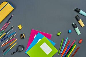 Flat lay photo of workspace desk with school accessories or office supplies on gray background.