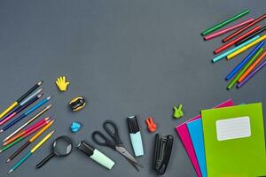 Flat lay photo of workspace desk with school accessories or office supplies on gray background.