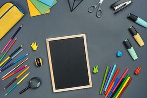 Flat lay photo of workspace desk with school accessories or office supplies on gray background.