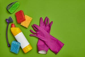 Detergents and cleaning accessories on a green background. Housekeeping concept. photo