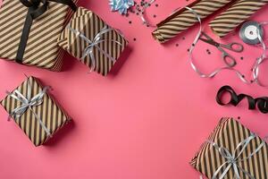 Different sizes, striped, brown gift boxes tied with black and silver ribbons and bows on a pink background. Close-up, copy space, top view. photo