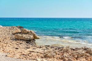 Disparo de un playa con piedras y transparente agua de el azur Mediterráneo mar, rodeado por un pintoresco naturaleza de Chipre. ayia napa. foto