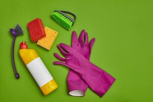 Detergents and cleaning accessories on a green background. Housekeeping concept. photo