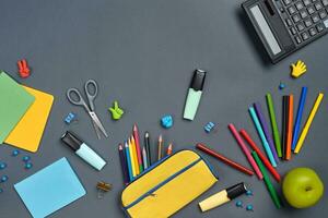 Flat lay photo of workspace desk with school accessories or office supplies on gray background.