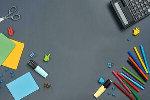 Flat lay photo of workspace desk with school accessories or office supplies on gray background.