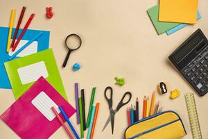 Flat lay photo of workspace desk with school accessories or office supplies on pink background.