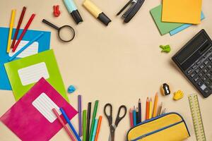 Flat lay photo of workspace desk with school accessories or office supplies on pink background.