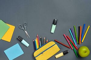 Flat lay photo of workspace desk with school accessories or office supplies on gray background.