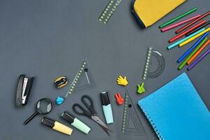 Flat lay photo of workspace desk with school accessories or office supplies on gray background.