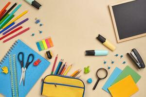 Flat lay photo of workspace desk with school accessories or office supplies on pink background.