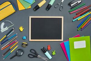 Flat lay photo of workspace desk with school accessories or office supplies on gray background.