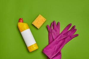 Detergents and cleaning accessories on a green background. Housekeeping concept. photo