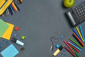 Flat lay photo of workspace desk with school accessories or office supplies on gray background.