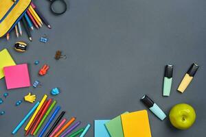 Flat lay photo of workspace desk with school accessories or office supplies on gray background.