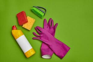 Detergents and cleaning accessories on a green background. Housekeeping concept. photo