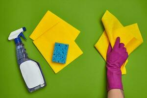 Detergents and cleaning accessories on a green background. Housekeeping concept. photo