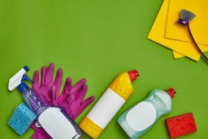 Detergents and cleaning accessories on a green background. Housekeeping concept. photo