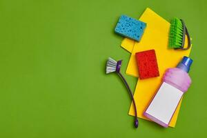 Detergents and cleaning accessories on a green background. Housekeeping concept. photo