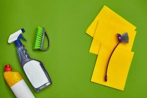 Detergents and cleaning accessories on a green background. Housekeeping concept. photo