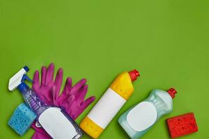 Detergents and cleaning accessories on a green background. Housekeeping concept. photo