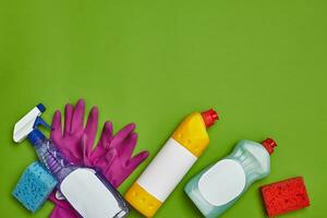 Detergents and cleaning accessories on a green background. Housekeeping concept. photo