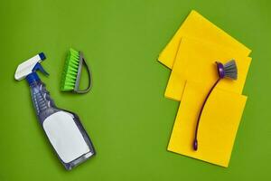 Detergents and cleaning accessories on a green background. Housekeeping concept. photo