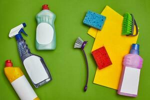 Detergents and cleaning accessories on a green background. Housekeeping concept. photo