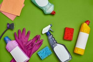 Detergents and cleaning accessories on a green background. Housekeeping concept. photo