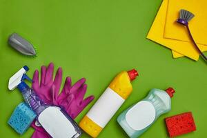 Detergents and cleaning accessories on a green background. Housekeeping concept. photo