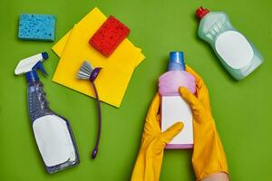 Detergents and cleaning accessories on a green background. Housekeeping concept. photo