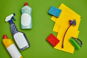 Detergents and cleaning accessories on a green background. Housekeeping concept. photo