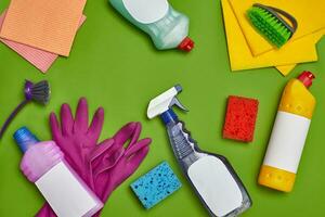 Detergents and cleaning accessories on a green background. Housekeeping concept. photo