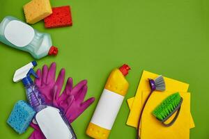 Detergents and cleaning accessories on a green background. Housekeeping concept. photo