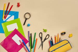 Flat lay photo of workspace desk with school accessories or office supplies on pink background.