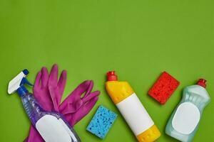 Detergents and cleaning accessories on a green background. Housekeeping concept. photo